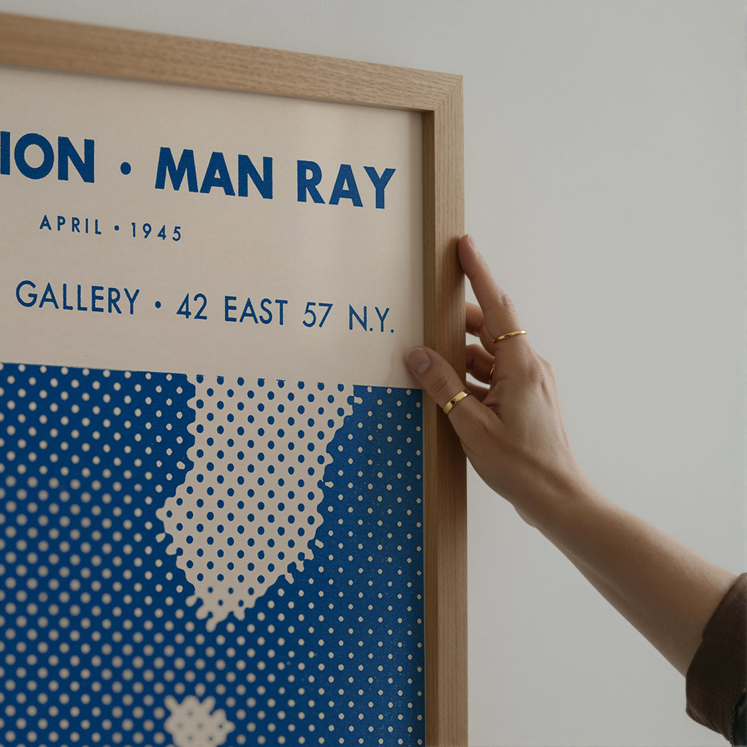 Man Ray Exhibition Poster with minimalist blue and beige graphic design, vintage style art print in wooden frame