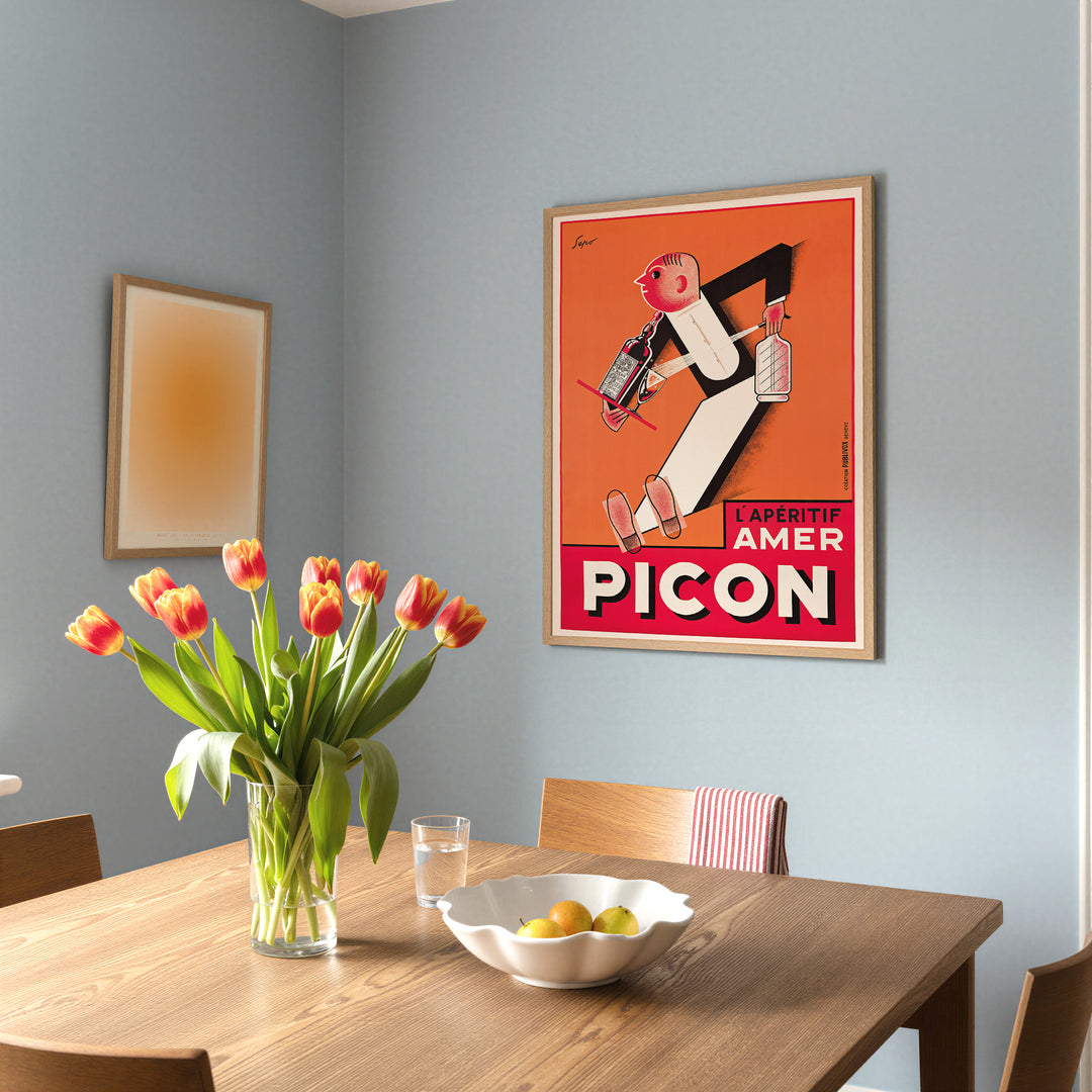 Picon Advertisement Poster vintage style with bold red and orange colors, featuring a stylized animated figure, framed poster.